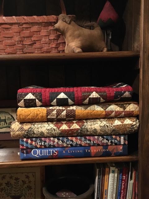 More folded quilts (made by me) in a bookshelf at home.